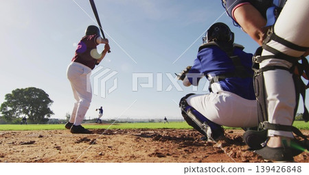 Batting, maroon batter swinging in batter's box at baseball field, catcher in blue gear, copy space 139426848