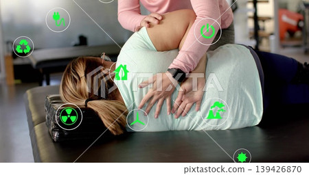 Mobilizing clinician placing hands on patient wearing leggings on table in clinic, with green icons Mobilizing clinician placing hands on patient wearing leggings on table in clinic, with green icons 139426870