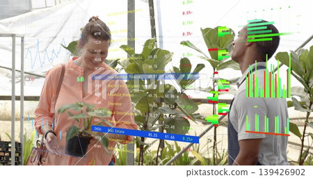 Checking leaf, apron-clad worker leaning in, peach-jacket visitor holding phone at nursery with AR 139426902