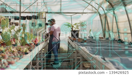 Inspecting two workers in apron and dark top using tablet in greenhouse, with AR overlay, cacti Inspecting two workers in apron and dark top using tablet in greenhouse, with AR overlay, cacti 139426925