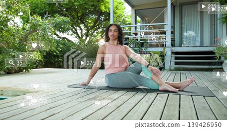 Twisting adult woman in pink top, leggings on dark mat on wooden deck, showing overlays, smartwatch Twisting adult woman in pink top, leggings on dark mat on wooden deck, showing overlays, smartwatch 139426950