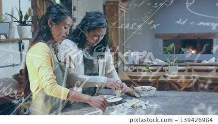 Preparing two women making lattice tart at wooden counter in home kitchen, with rolling pin, aprons Preparing two women making lattice tart at wooden counter in home kitchen, with rolling pin, aprons 139426984