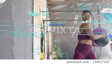 Holding purple medicine ball, woman in maroon workout set standing in gym, HUD overlays, copy space 139427102