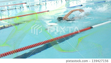 Swimming woman performing freestyle at lap pool, wearing cap, goggles, swimsuit, passing lane ropes Swimming woman performing freestyle at lap pool, wearing cap, goggles, swimsuit, passing lane ropes 139427156