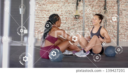 Doing workout two women wearing sports bras on gym mat holding medicine balls with AR overlay Doing workout two women wearing sports bras on gym mat holding medicine balls with AR overlay 139427201