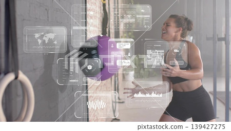 Striking athlete in black sportswear hitting purple rebound ball in gym with AR panels, copy space Striking athlete in black sportswear hitting purple rebound ball in gym with AR panels, copy space 139427275