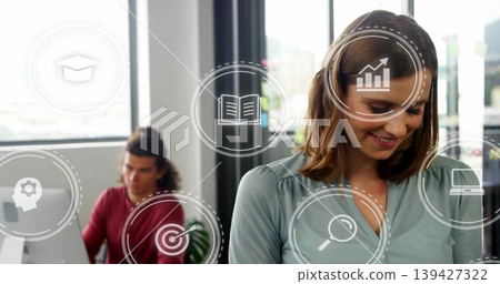 Smiling woman in teal blouse looking down in office, overlaid icons, male using computer Smiling woman in teal blouse looking down in office, overlaid icons, male using computer 139427322