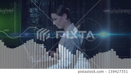 Working tech wearing white blazer typing on laptop at data center with server racks, overlays Working tech wearing white blazer typing on laptop at data center with server racks, overlays 139427351