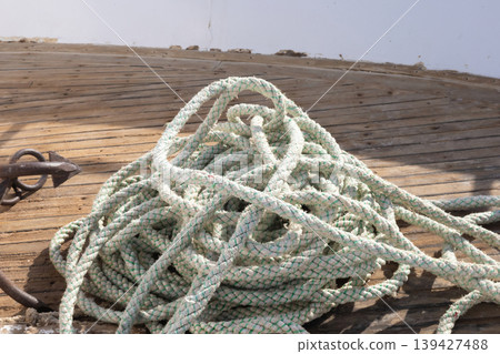 Nautical rope coil on weathered deck capturing maritime charm Nautical rope coil on weathered deck capturing maritime charm 139427488