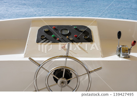 Nautical steering wheel on boat overlooking blue ocean for marine navigation concept 139427495