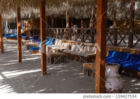 Tranquil outdoor lounge with wooden canopy and rustic seating 139427534
