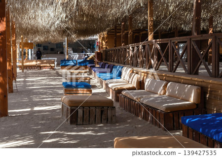 Tranquil beachside lounge with wooden seating and dappled sunlight 139427535