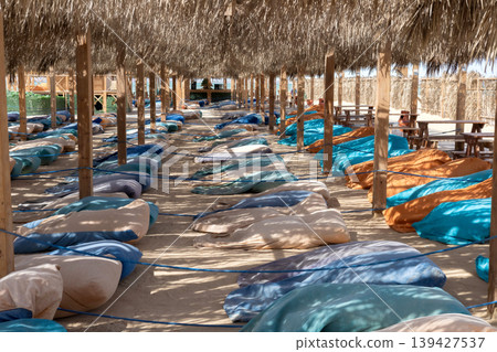 Relaxing outdoor seating area under thatched roof with colorful cushions 139427537