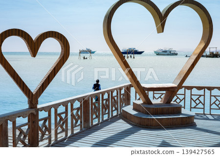 Scenic coastal view with wooden heart sculptures overlooking the ocean horizon Scenic coastal view with wooden heart sculptures overlooking the ocean horizon 139427565