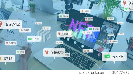 Displaying main laptop showing NFT chart at office desk, team in shirts holding printed report 139427622