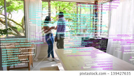 Viewing smartphone, masked colleagues examining AR overlay near large windows in bright room, table 139427635