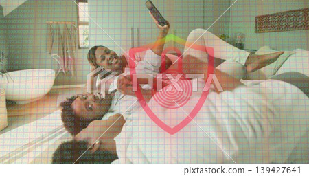 Raising smartphone, three women in red top and white shorts reclining on white bed, shield overlay 139427641