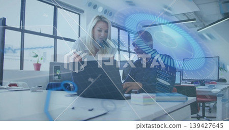 Leaning woman guiding typing colleague in businesswear, using laptop at open office, AR overlays Leaning woman guiding typing colleague in businesswear, using laptop at open office, AR overlays 139427645