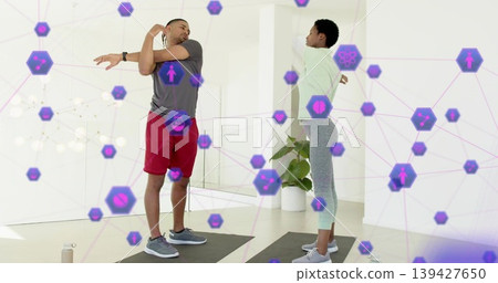 Stretching exercise partners extending arms on mats at home in sportswear with purple AR icons Stretching exercise partners extending arms on mats at home in sportswear with purple AR icons 139427650
