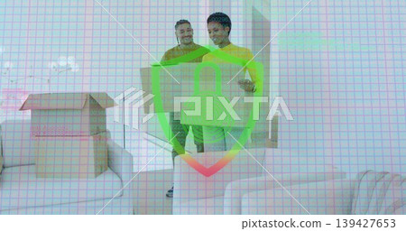 Carrying two adults in yellow tops lifting large cardboard box in living room, security overlay 139427653