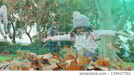 Jumping child wearing pom-pom knit hat, sweater landing into brown leaf pile at park with rake Jumping child wearing pom-pom knit hat, sweater landing into brown leaf pile at park with rake 139427702