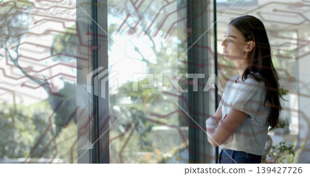 Standing woman wearing stripes gazing past glass at garden with hex map, plant nearby, copy space Standing woman wearing stripes gazing past glass at garden with hex map, plant nearby, copy space 139427726