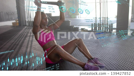 Doing core hold, woman holding bar overhead on rubber floor, wearing magenta sports set with HUD Doing core hold, woman holding bar overhead on rubber floor, wearing magenta sports set with HUD 139427852