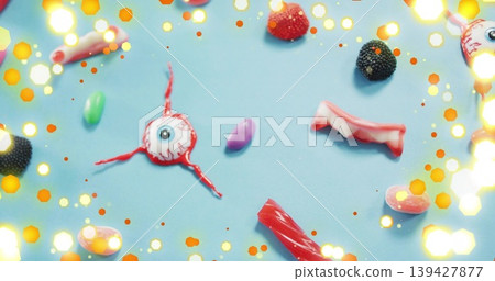 Displaying eyeball gummy with 3 red licorice strands sitting on pale blue mat, with vampire teeth Displaying eyeball gummy with 3 red licorice strands sitting on pale blue mat, with vampire teeth 139427877