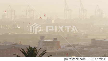 Framing harbor skyline under hazy light, showing gantry cranes, warehouses, palm fronds, red marks Framing harbor skyline under hazy light, showing gantry cranes, warehouses, palm fronds, red marks 139427951