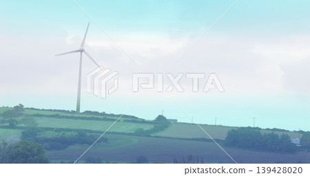 Spinning white wind turbine sweeping blades on low ridge over farm fields, hedgerows, utility poles Spinning white wind turbine sweeping blades on low ridge over farm fields, hedgerows, utility poles 139428020