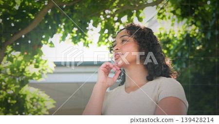 Standing woman wearing knit top under tree leaves, hand on chin, eave, dappled light, copy space 139428214