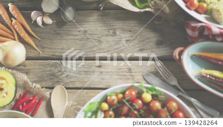 Displaying white bowl holding cherry tomatoes and greens on rustic wooden tabletop, with spoon Displaying white bowl holding cherry tomatoes and greens on rustic wooden tabletop, with spoon 139428264