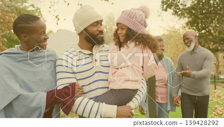 Holding child, mid-adult man cradling girl in park, in striped sweater, beanie, hexagon overlays Holding child, mid-adult man cradling girl in park, in striped sweater, beanie, hexagon overlays 139428292