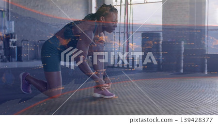 Kneeling woman in dark athletic gear tying purple running shoe on rubber gym mat, digital overlay Kneeling woman in dark athletic gear tying purple running shoe on rubber gym mat, digital overlay 139428377
