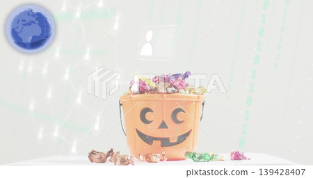 Showing pumpkin bucket holding foil candies on white table with blue globe icon and digital motifs 139428407