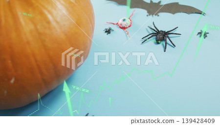 Sitting large orange pumpkin on pale blue table, showing spiders eyeball bat neon chart, copy space Sitting large orange pumpkin on pale blue table, showing spiders eyeball bat neon chart, copy space 139428409