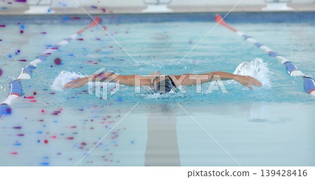Cutting female swimmer in dark one-piece, swim cap and goggles in pool between dividers, splashing Cutting female swimmer in dark one-piece, swim cap and goggles in pool between dividers, splashing 139428416
