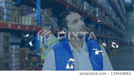 Observing man in blue vest and headset watching worker scanning boxes in hi-vis vest, AR icons Observing man in blue vest and headset watching worker scanning boxes in hi-vis vest, AR icons 139428663