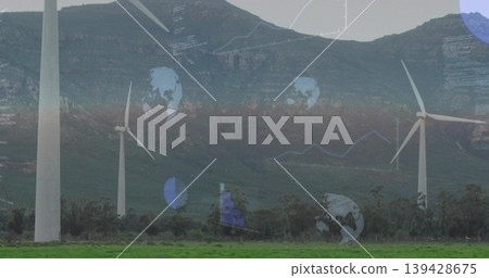 Towering wind turbines rotating across grassy pasture below mountain ridge, showing globe icons Towering wind turbines rotating across grassy pasture below mountain ridge, showing globe icons 139428675