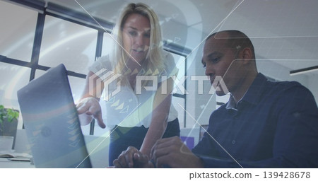 Pointing woman white blouse guiding man dark shirt typing laptop at office desk, plant 139428678