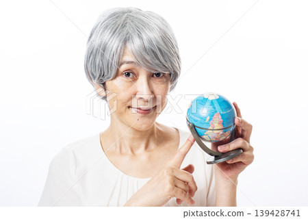 一位老婦人用食指指著地球儀，直視鏡頭。 139428741