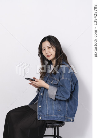 一位年輕女子坐在椅子上操作手機 一位年輕女子坐在椅子上操作手機 139428798