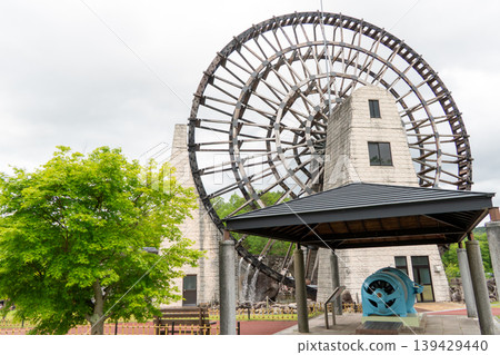 A giant wooden waterwheel stands tall at the Obaachan-ichi Yamaoka roadside station. 139429440