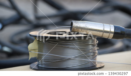 Welding wire spool and MIG gun nozzle ready for metal fabrication work 139430297