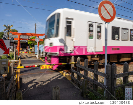 A railway crossing on the approach to the shrine where trains pass: An unusual railway scene and torii gate at Ukyozuka Shrine 139430488