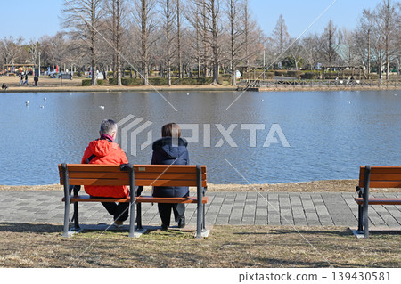 冬日午後,在水本公園聊天;並排坐在長椅上的兩個人的背影反映了寧靜的日常生活。 冬日午後,在水本公園聊天;並排坐在長椅上的兩個人的背影反映了寧靜的日常生活。 139430581