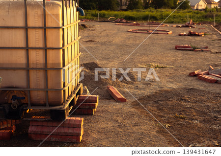 A large water tank and paving stones on a construction site at sunset 139431647