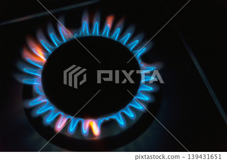 Blue and orange gas flames burning on a kitchen stove burner in the dark Blue and orange gas flames burning on a kitchen stove burner in the dark 139431651