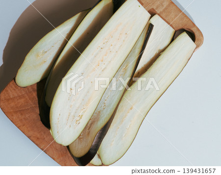 Long slices of raw eggplant on a wooden cutting board Long slices of raw eggplant on a wooden cutting board 139431657