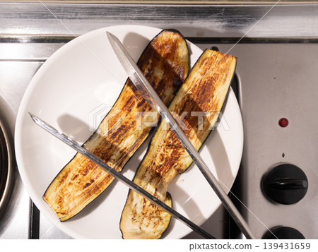 Grilled eggplant slices on a white plate with metal kitchen tongs Grilled eggplant slices on a white plate with metal kitchen tongs 139431659